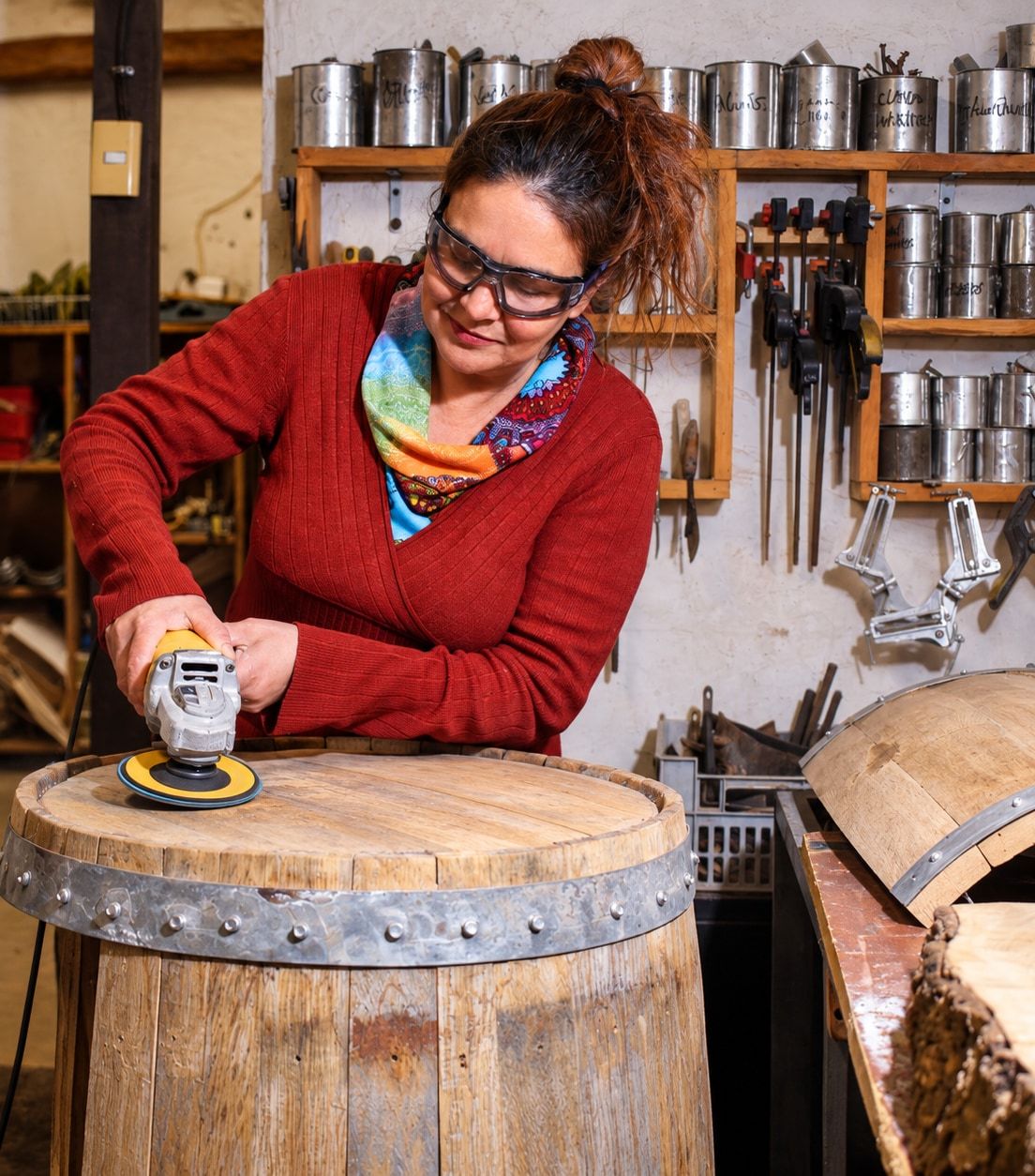 Alda lija con una herramienta eléctrica la tapa de una barrica de madera en el taller.